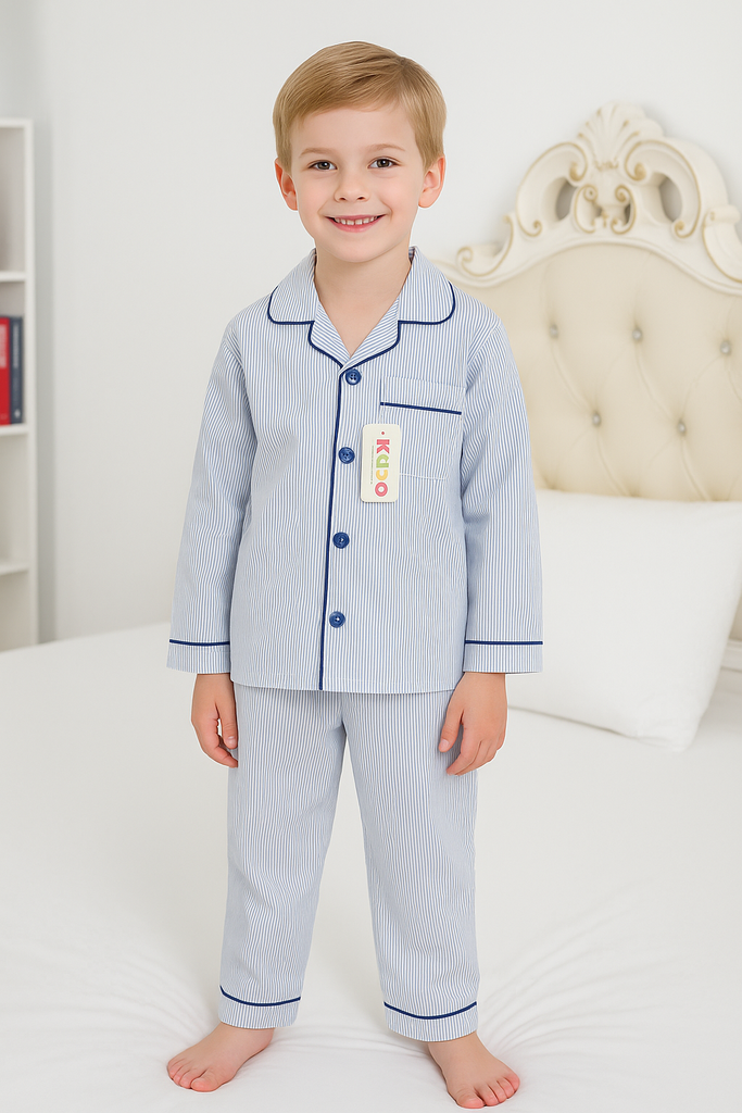 Child wearing a blue striped pajama set with a visible brand tag, sitting on a white bed.